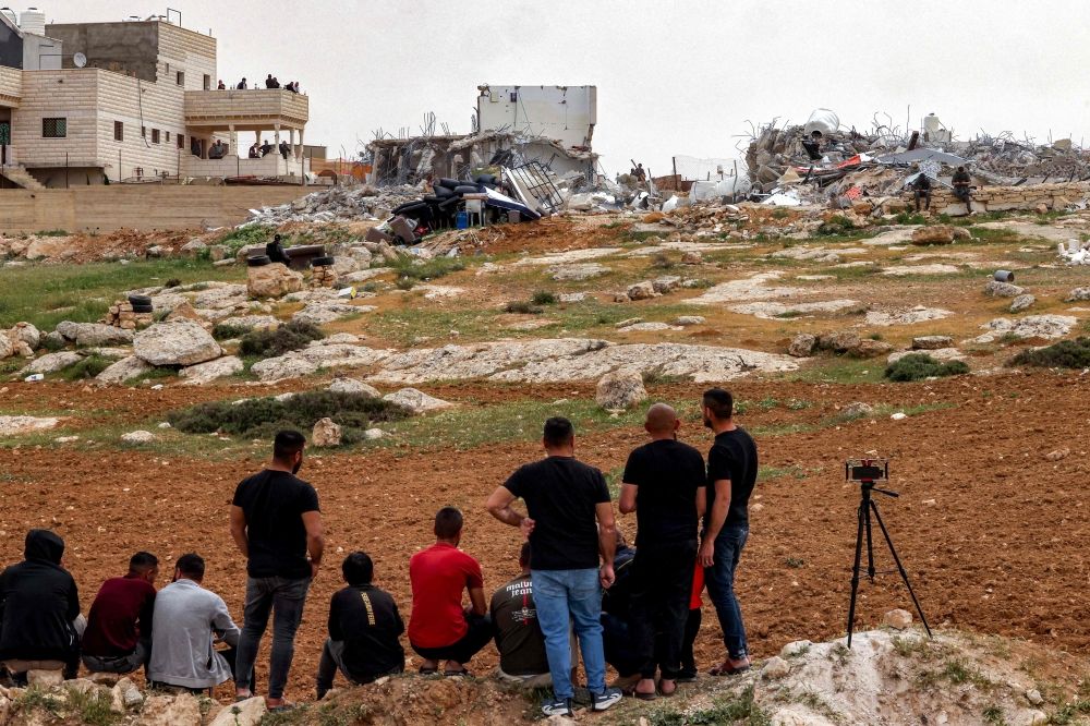 يراقب الفلسطينيون حفارات الاحتلال وهي تهدم مبانٍ فلسطينية في الضفة الغربية- أ ف ب