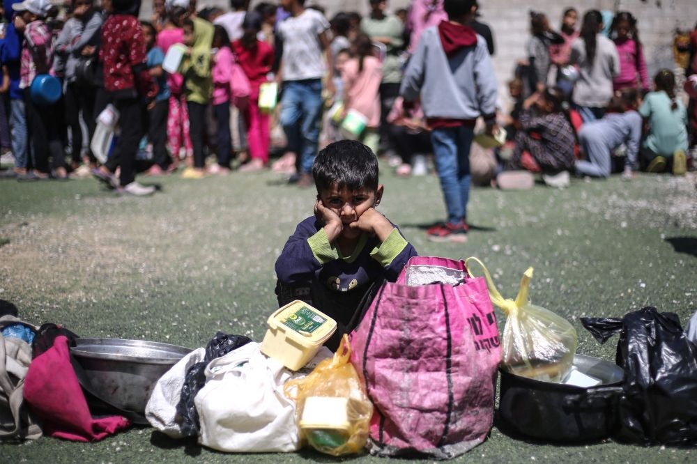 طفل فلسطيني ينتظر الحصول على وجبة في مخيم النصيرات وسط قطاع غزة - أ ف ب